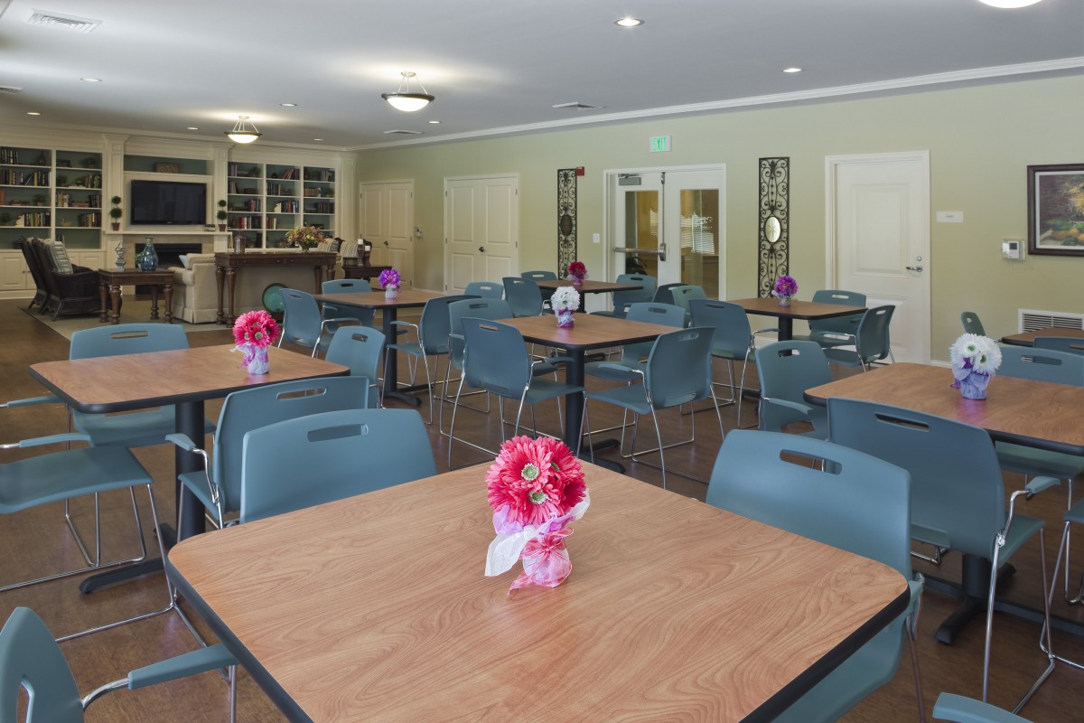 An empty dining area with tables and chairs, decorated with flowers.