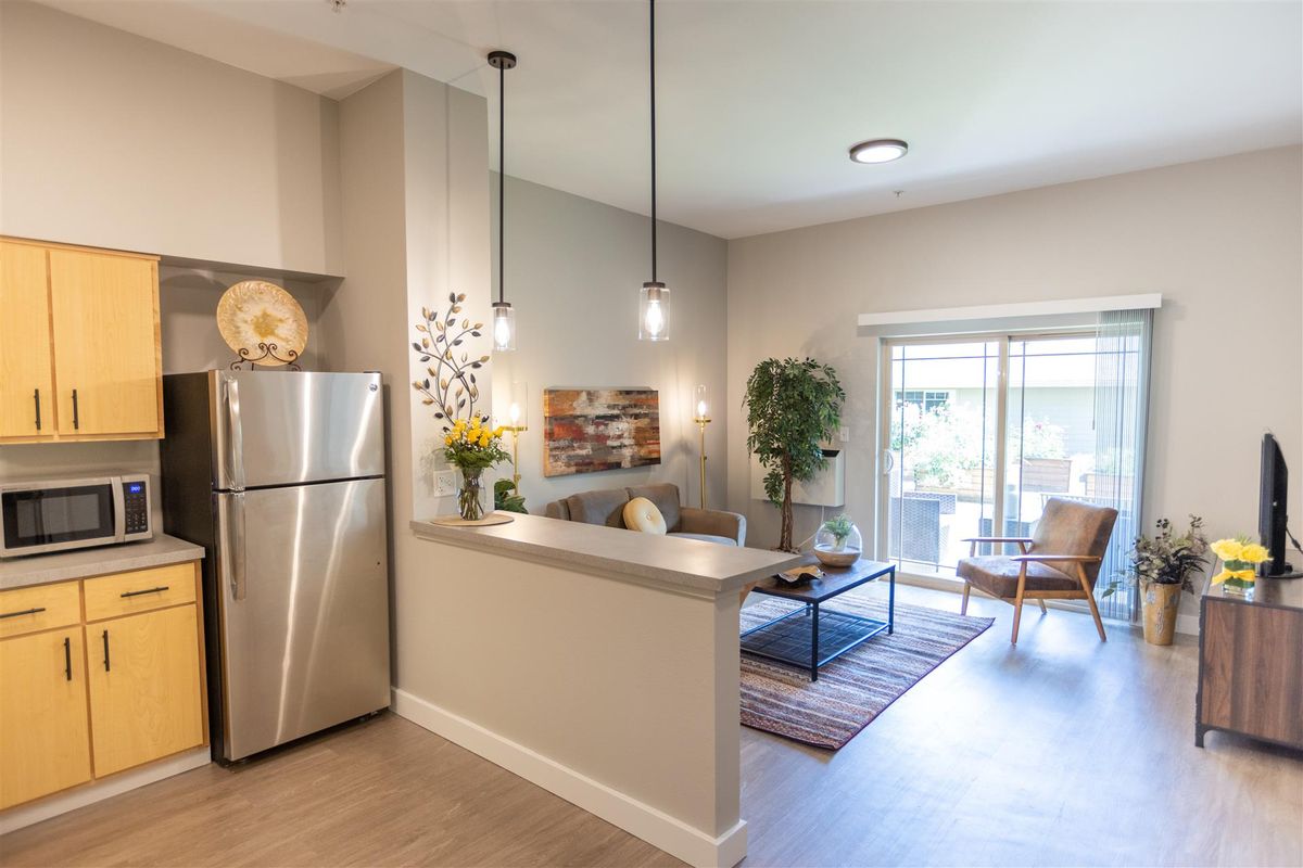 A modern open-concept living area with a cozy atmosphere, featuring a kitchen and a living room with stylish decor.