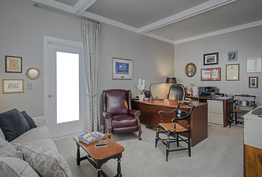 A cozy home office with a desk, chairs, and various decorations.