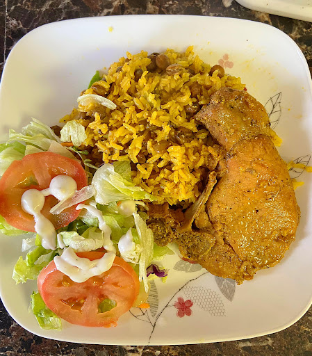 A delicious plate featuring fried chicken, spiced yellow rice, and a fresh salad with tomatoes.