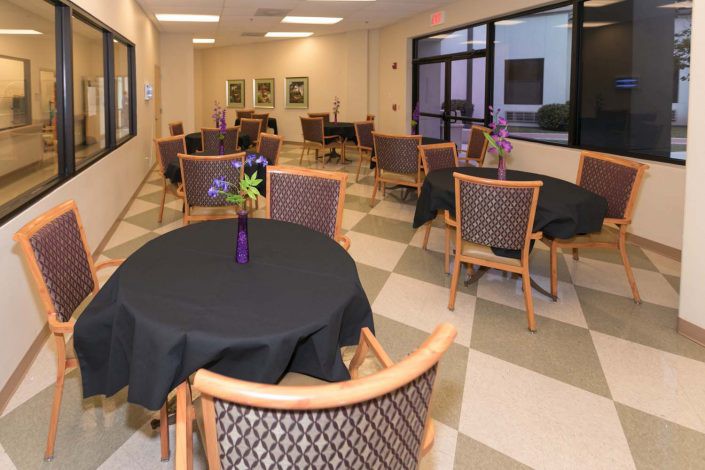 A cozy dining area with several tables and chairs, decorated with vases of flowers.