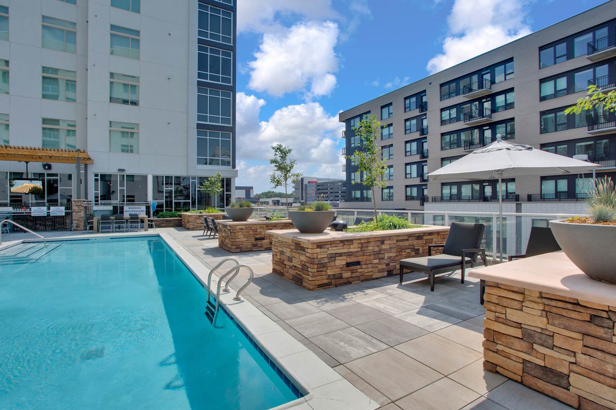 A modern apartment complex featuring an outdoor pool and lounging area.