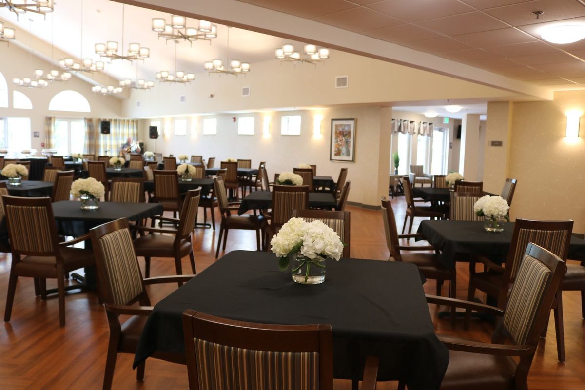 A well-furnished dining area with elegantly arranged tables and chairs, adorned with flower centerpieces.