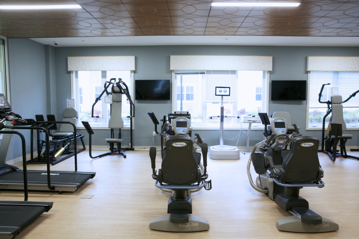 A well-lit gym interior with various exercise machines and fitness equipment.