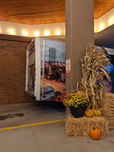 A truck partially parked near autumn decorations, featuring pumpkins and hay.