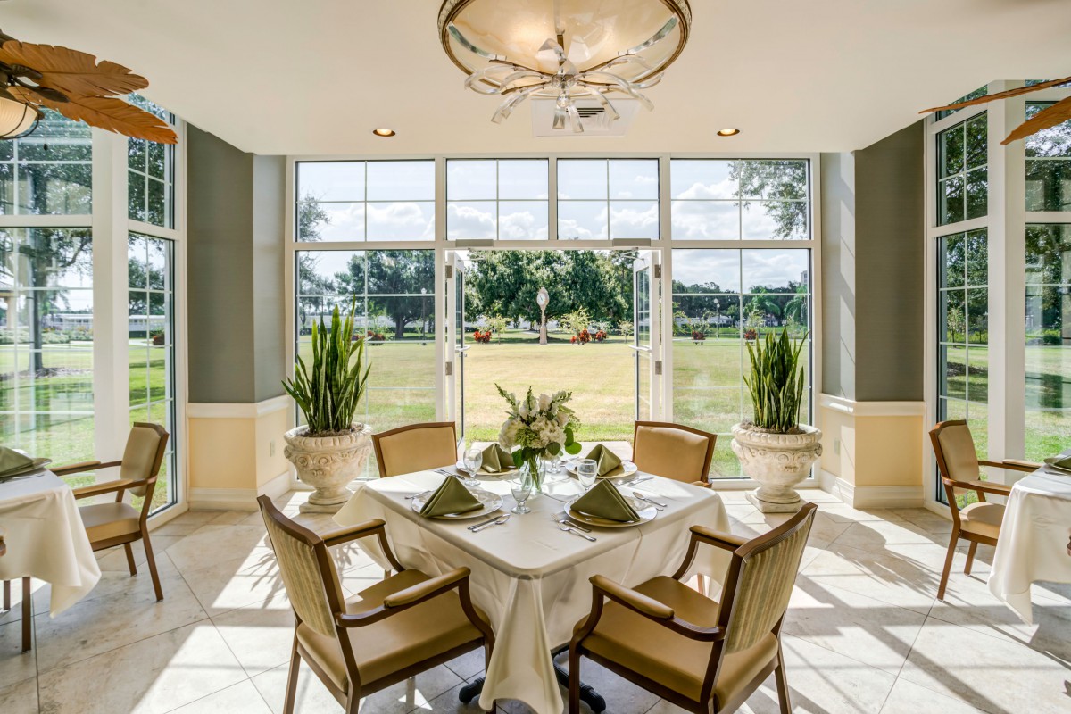 A beautifully set dining table in a well-lit room with large windows offering an expansive view of the outdoors.