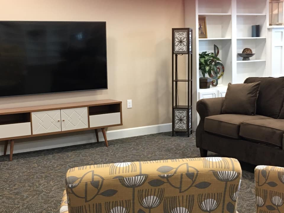 A cozy living room with a television, shelf, and comfortable seating.