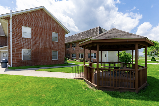 A peaceful outdoor area featuring a gazebo and well-maintained lawns surrounded by residential buildings.