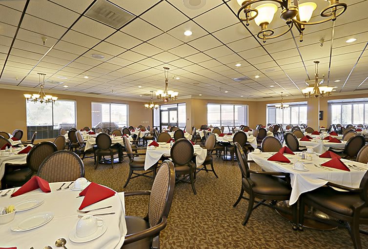 A spacious banquet hall with neatly arranged tables and chairs, set for dining.