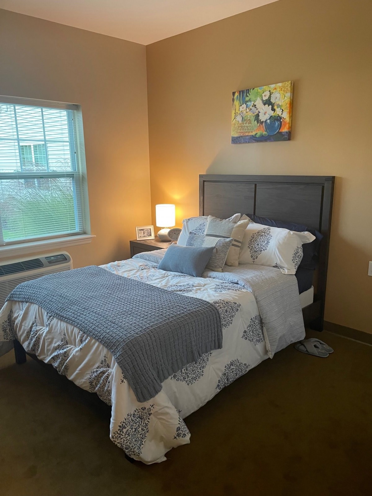 A cozy bedroom with a neatly made bed, soft pillows, and warm lighting.