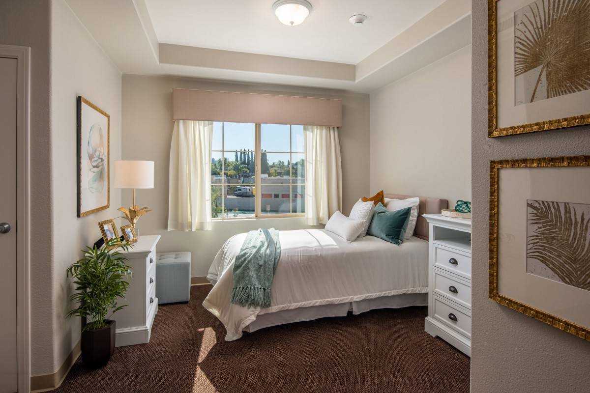 A cozy and well-decorated bedroom with a large window, featuring neutral tones and stylish furniture.