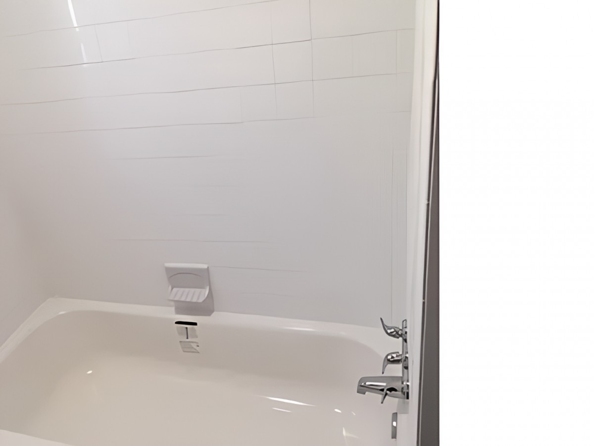 A clean bathroom with a white bathtub and tiled walls.