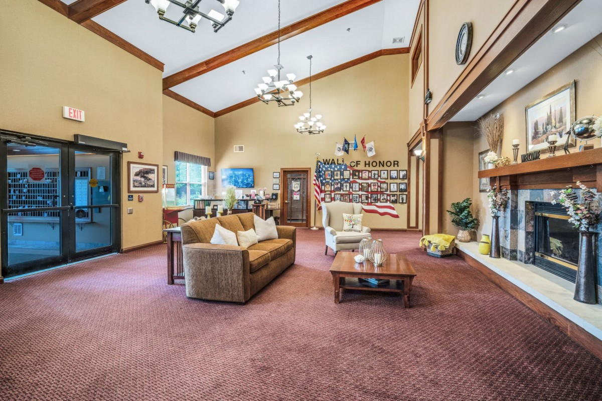 A cozy living room with comfortable seating, decorative elements, and a high ceiling.
