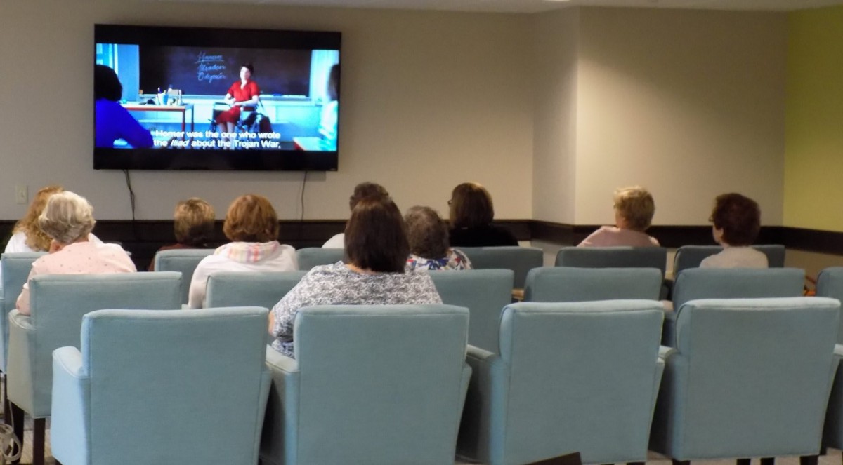 People seated in a waiting room watching television.