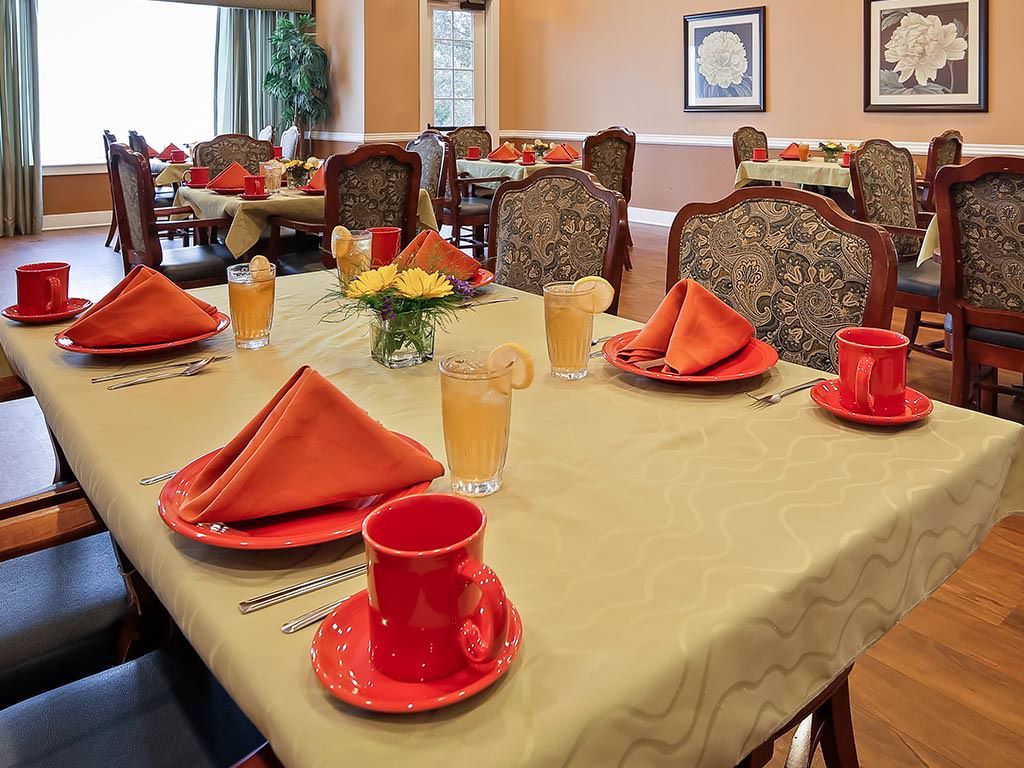 A well-set dining table with orange napkins and red cups in a stylish dining room.