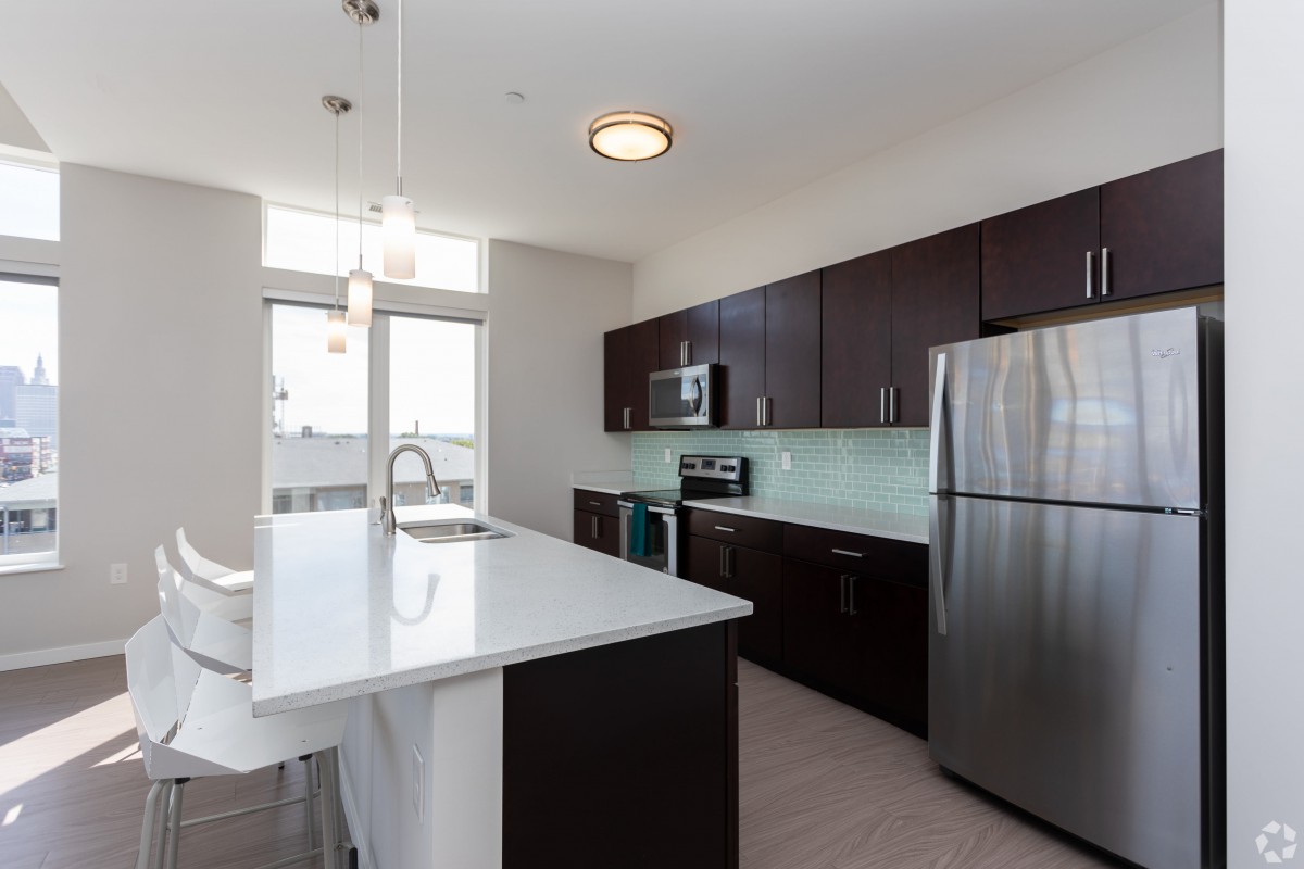 A modern kitchen with a large island, stainless steel appliances, and sleek dark cabinets.