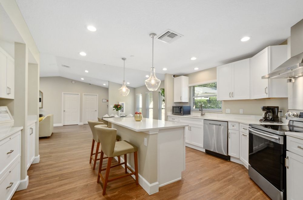 A spacious and modern kitchen with an island, white cabinets, and wood flooring.