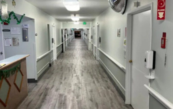 A long, well-lit hallway in a hospital with doors on either side.