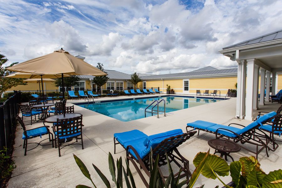 A serene outdoor swimming pool area with lounge chairs and umbrellas under a cloudy sky.