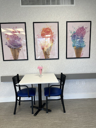 A cozy ice cream parlor featuring colorful cone artwork on the walls and a simple dining setup.