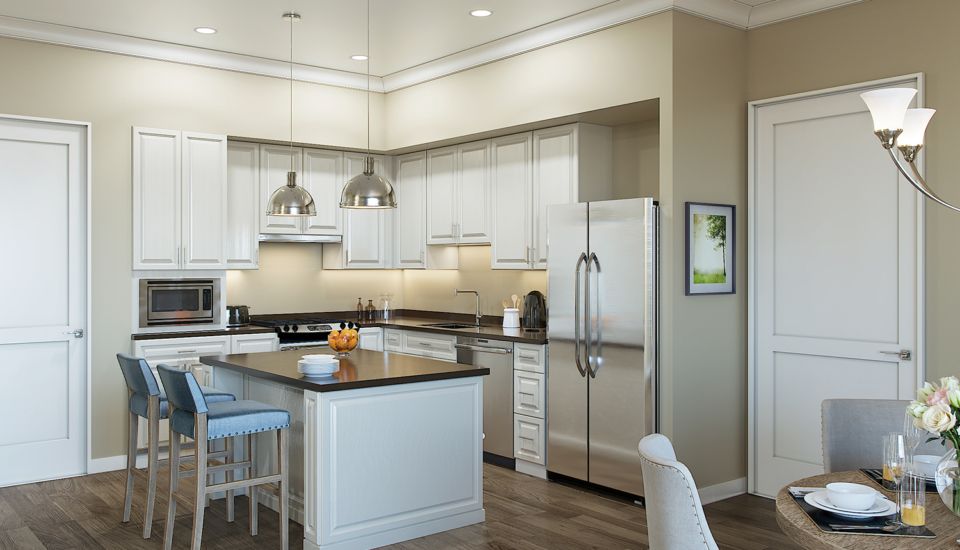 A modern kitchen with white cabinets, an island, and stainless steel appliances.