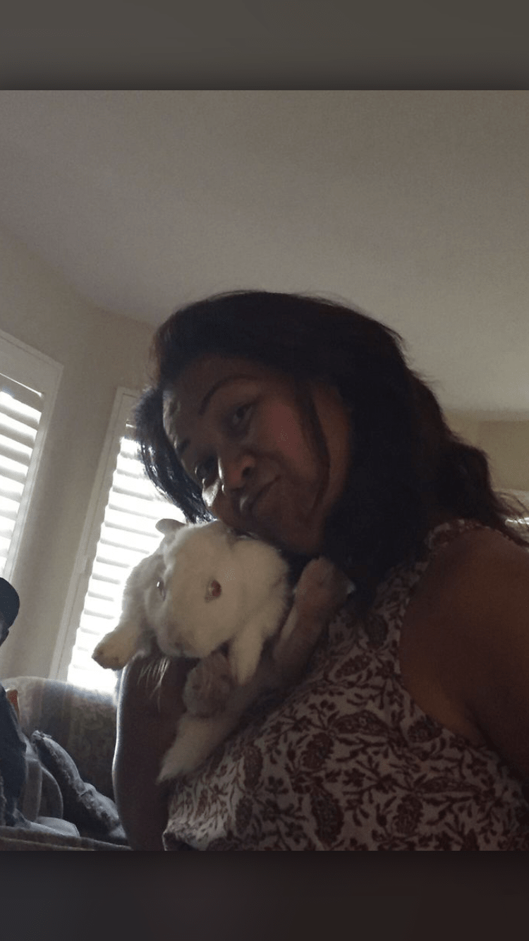 A woman lovingly holds her pet rabbit inside a home.
