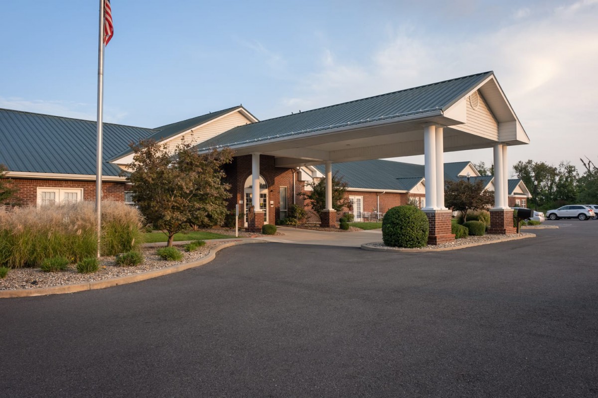 The image shows a building with a large covered entrance and well-maintained landscaping.