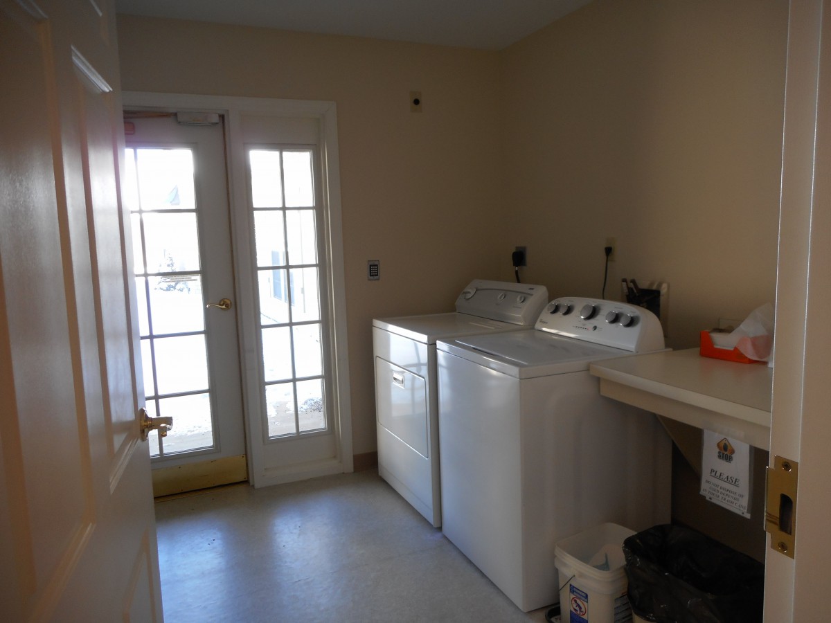 A well-lit laundry room featuring a washing machine and dryer next to a glass door.