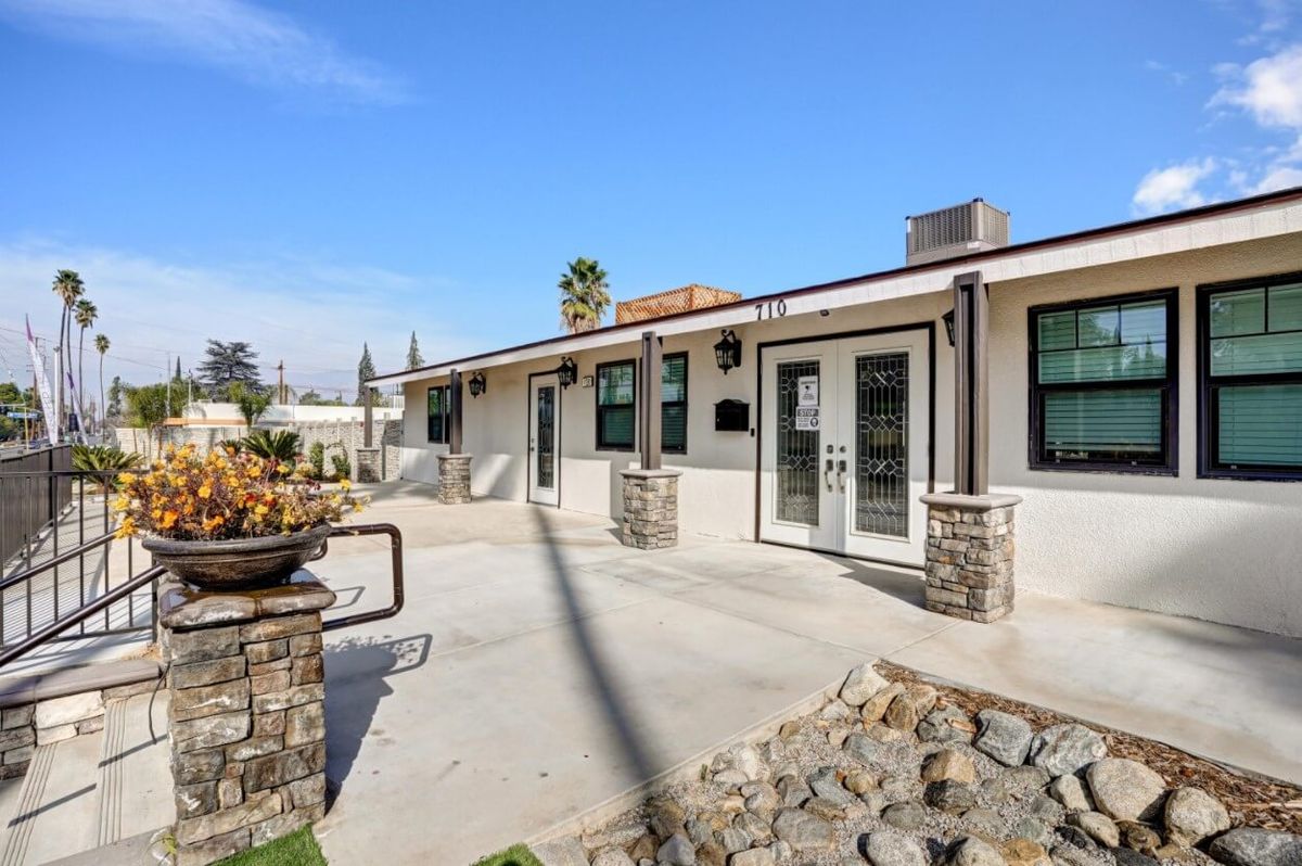 A modern single-story house exterior with a spacious patio and large windows.
