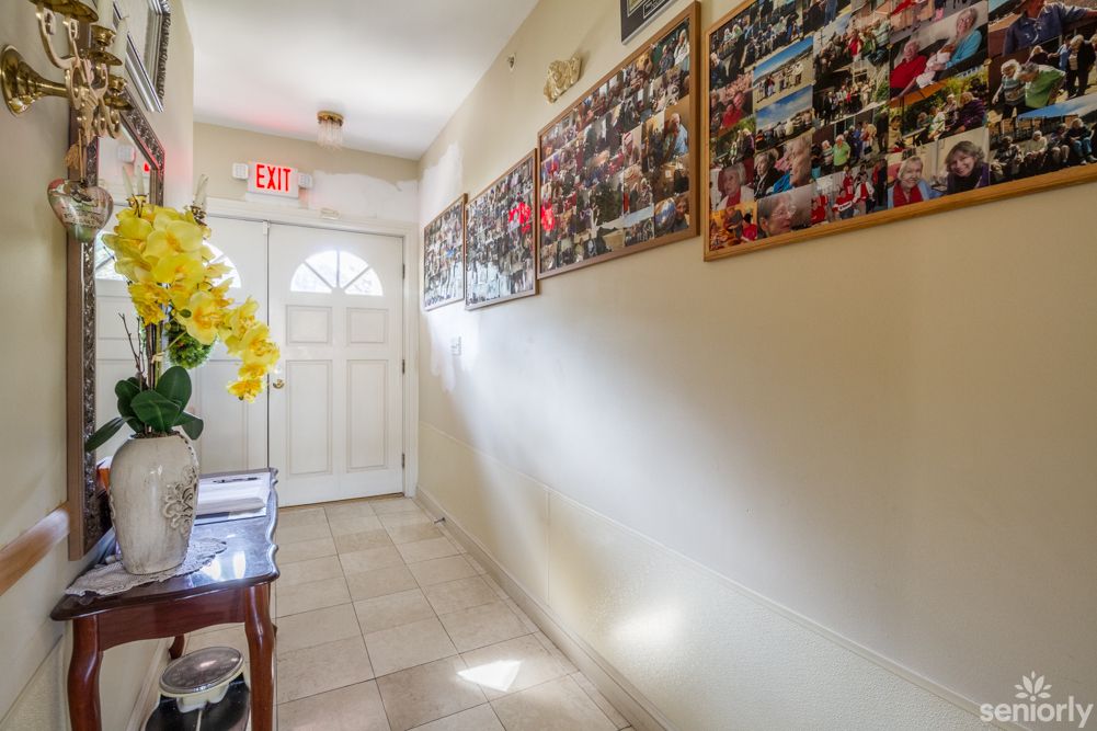 A well-lit hallway with photo collages on the wall and a decorative table with flowers near the entrance door.