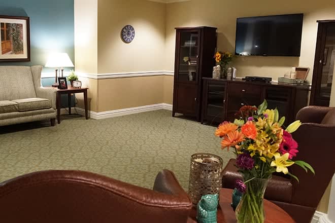 A cozy living room with a TV, cabinet, and floral decorations.