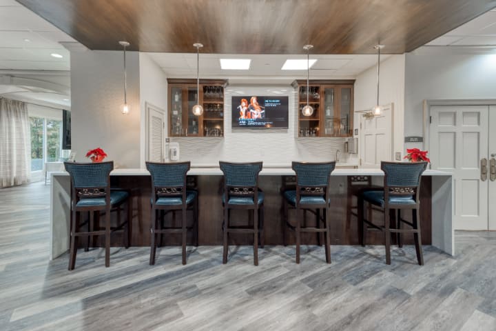 A modern bar area with sleek stools and a large TV on the wall.