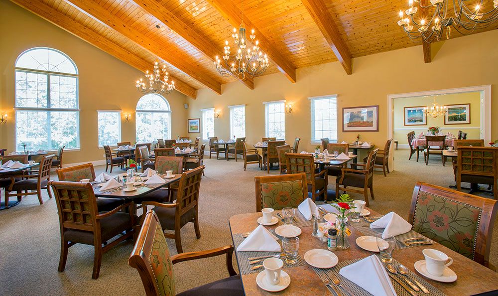 An elegant dining room with wooden ceilings, chandeliers, and neatly set tables.