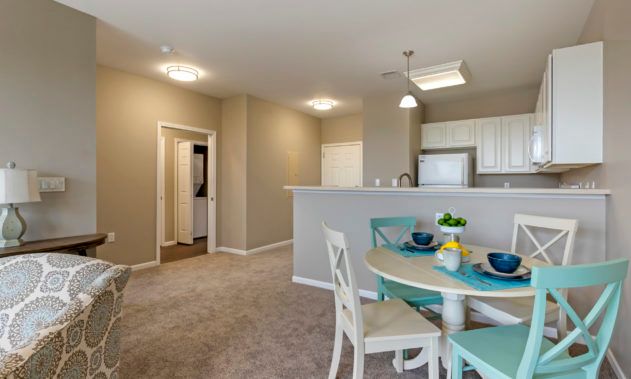 A modern open-concept living space featuring a dining area with turquoise accents and an adjacent kitchen.