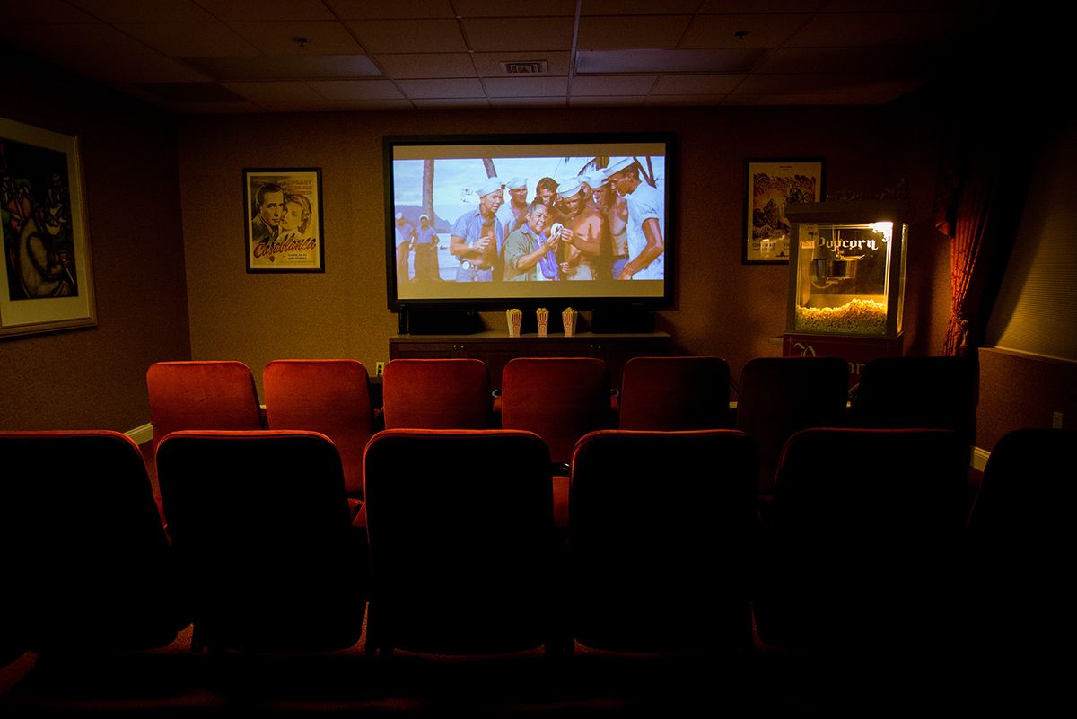 An empty cinema screening room with a movie playing on the screen.