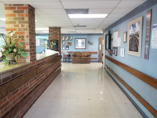 A view of a hospital corridor featuring a reception desk and artwork on the walls.