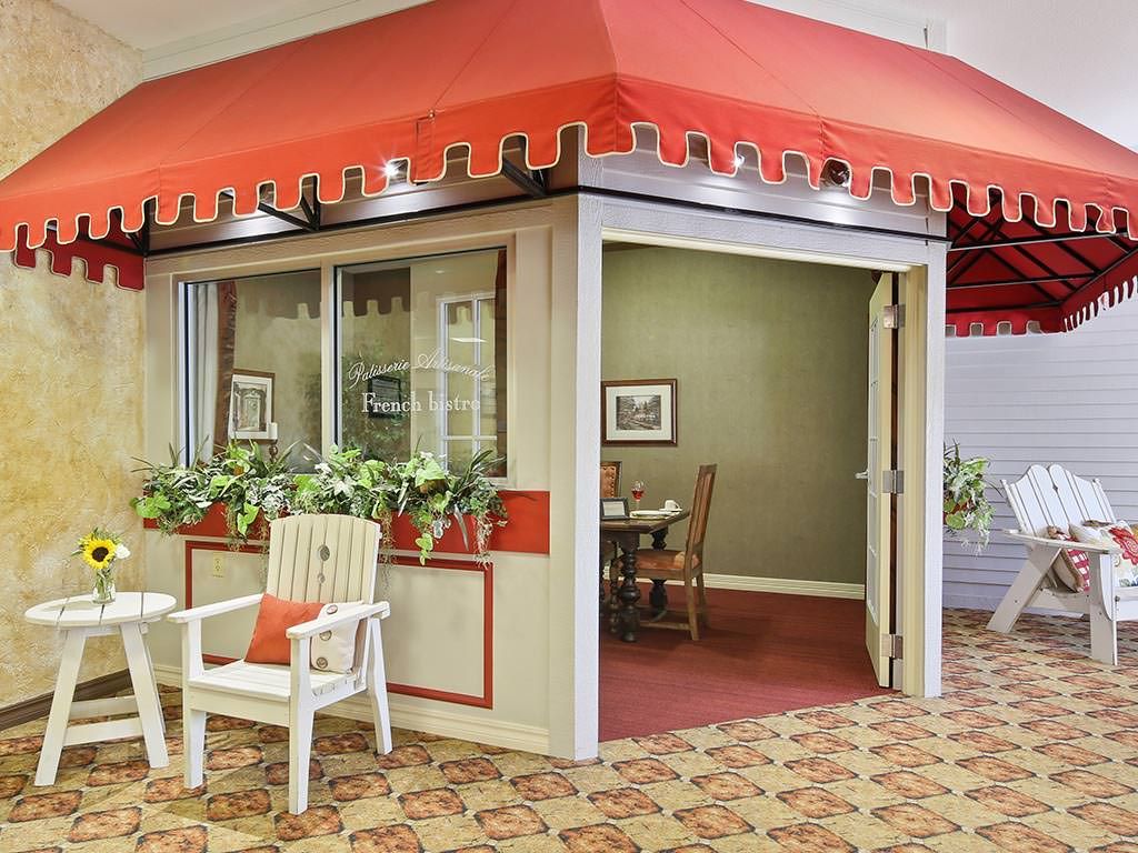 An indoor setup resembling a small cafe or shop with a red awning and seating.