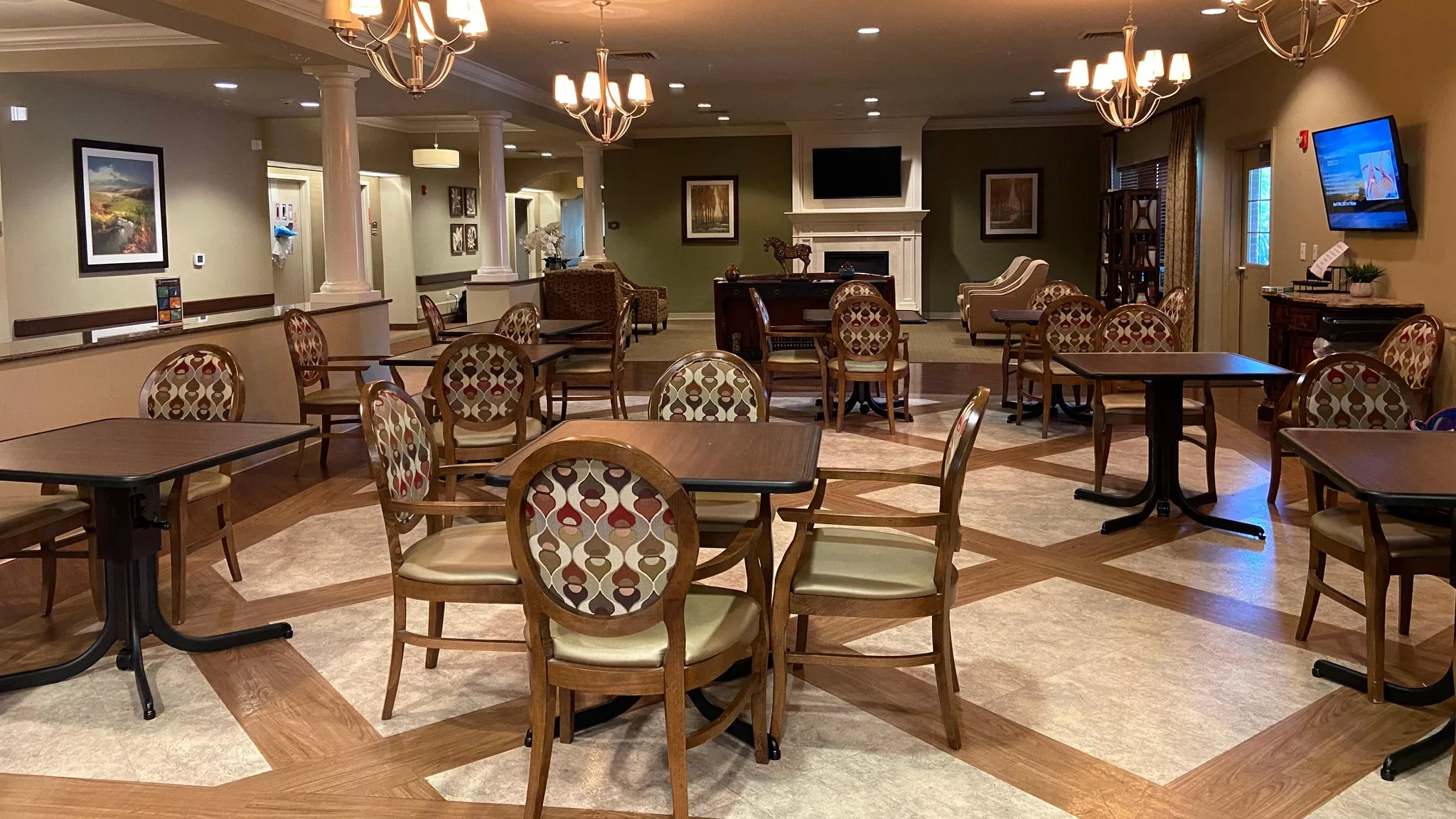 A cozy dining area with elegant chandeliers, patterned chairs, and a fireplace.