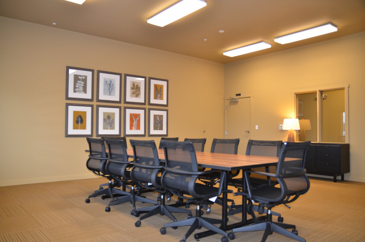 A modern conference room with a long table, chairs, and wall art.