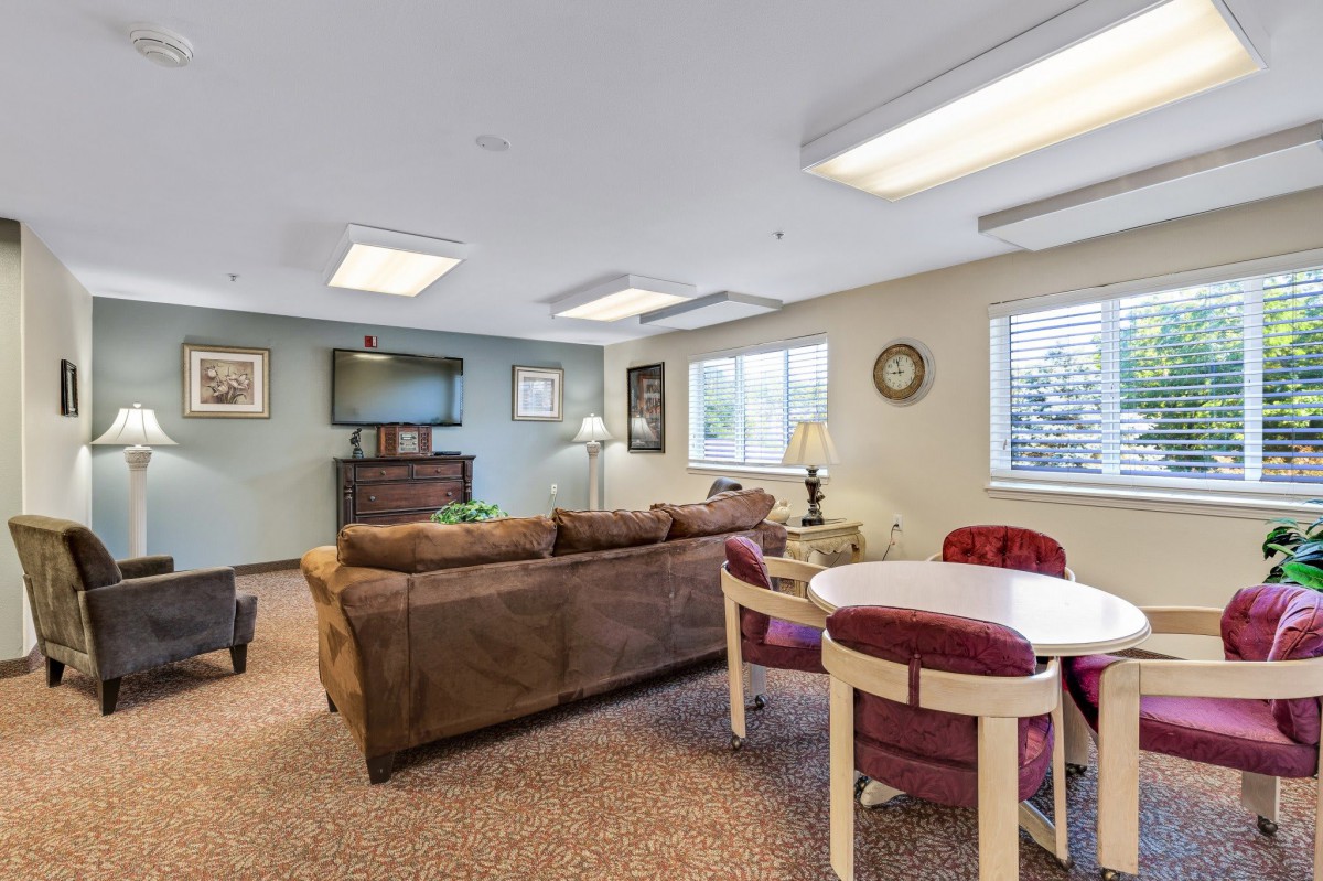 A cozy living room with a sofa, television, and dining table, featuring warm lighting and tasteful decor.