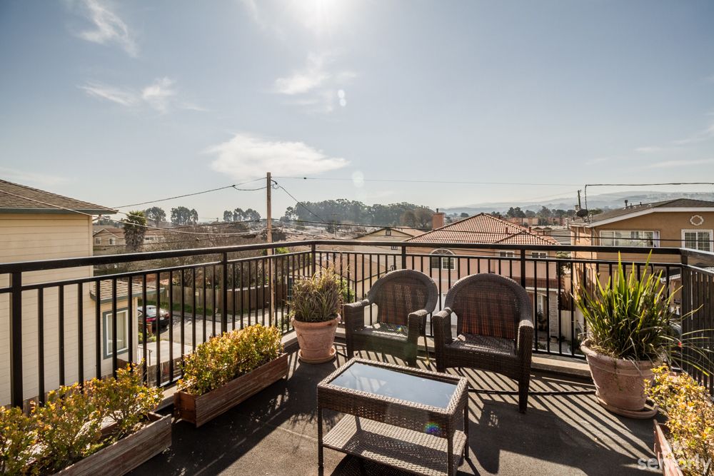 A sunny balcony with comfortable seating and potted plants, offering a scenic view.