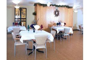 A well-decorated dining area with neatly arranged tables and chairs, featuring elegant table settings.