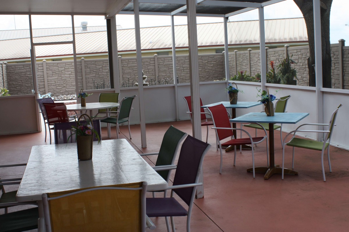 An outdoor patio area with empty tables and colorful chairs.