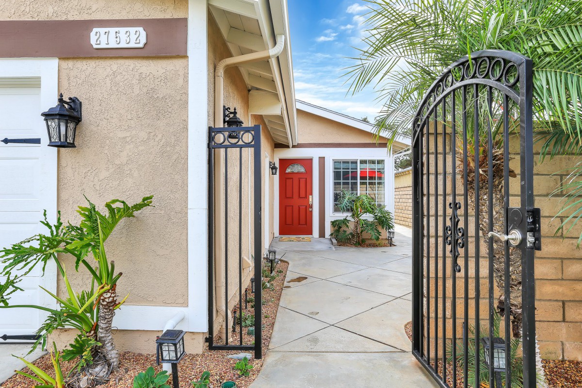 A welcoming entrance to a house with a red door and a garden gate.
