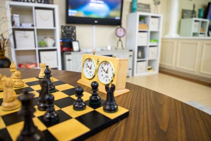 A chessboard with a clock set up in a cozy room, ready for a game.