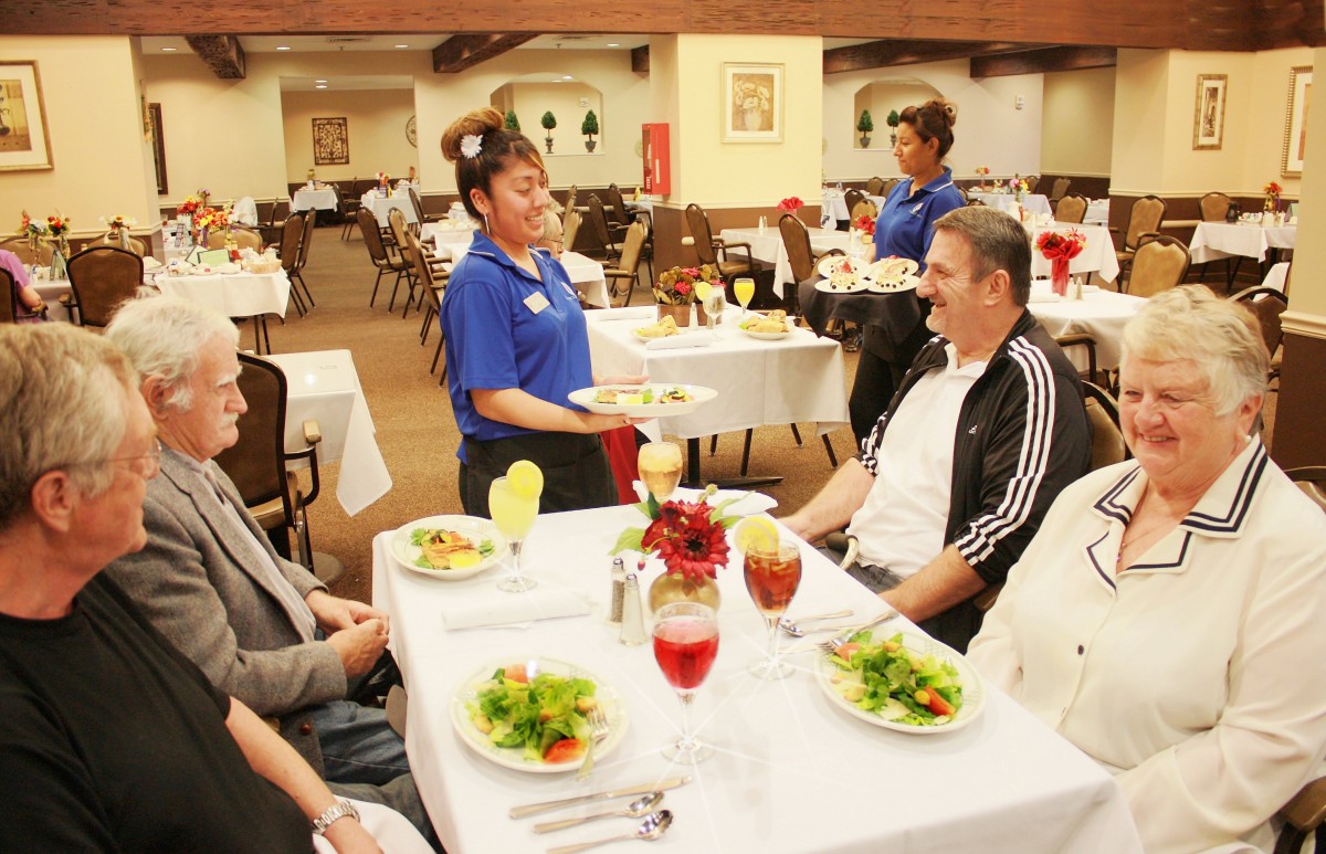 A waiter serves food to customers at a restaurant.
