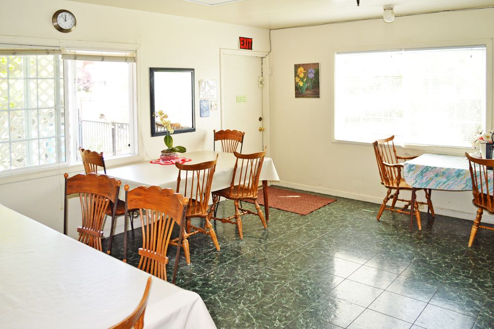 A cozy dining area with wooden chairs and tables, illuminated by natural light.