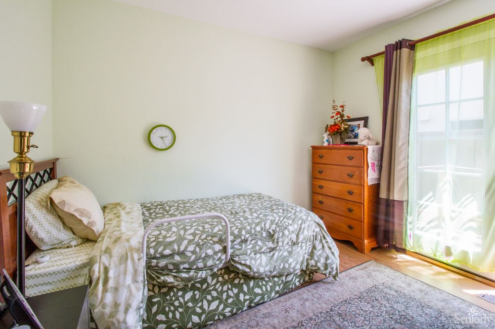 A cozy bedroom with a bed, dresser, and window with curtains.