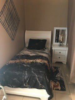 A cozy bedroom with a single bed and a nightstand, featuring a mirror.