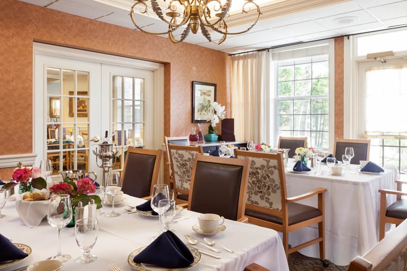 An elegant dining room with neatly set tables and a chandelier.